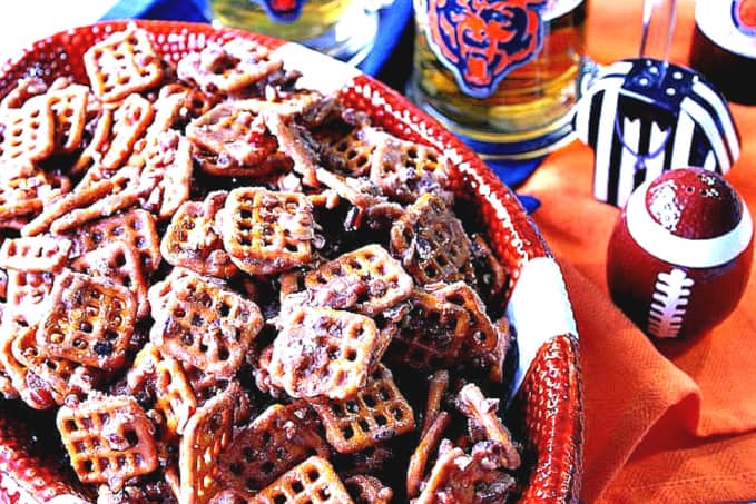 A football bowl filled with Cinnamon Praline Pretzels along with some football accessories in the background.