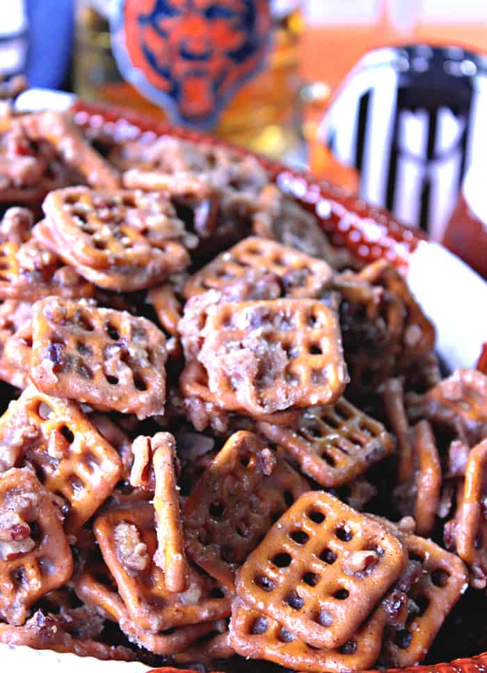 A closeup vertical photo a of bowl filled with Cinnamon Praline Pretzels and some football accessories in the background