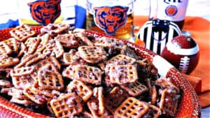 A football bowl filled with Cinnamon Praline Pretzels along with some football accessories in the background.