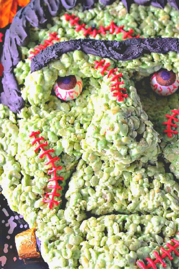 A super closeup photo of Frankenstein rice krispies treat along with gumball bloodshot eyes and royal icing stitches.