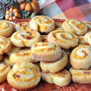A stack of Pumpkin Crescent Pinwheel Appetizers on an orange platter.