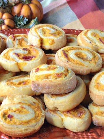 A stack of Pumpkin Crescent Pinwheel Appetizers on an orange platter.