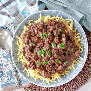A round blue plate filled with Ground Beef Sauerbraten Goulash over noodles.