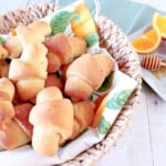 A basket filled with golden Homemade Crescent Rolls with honey and orange.