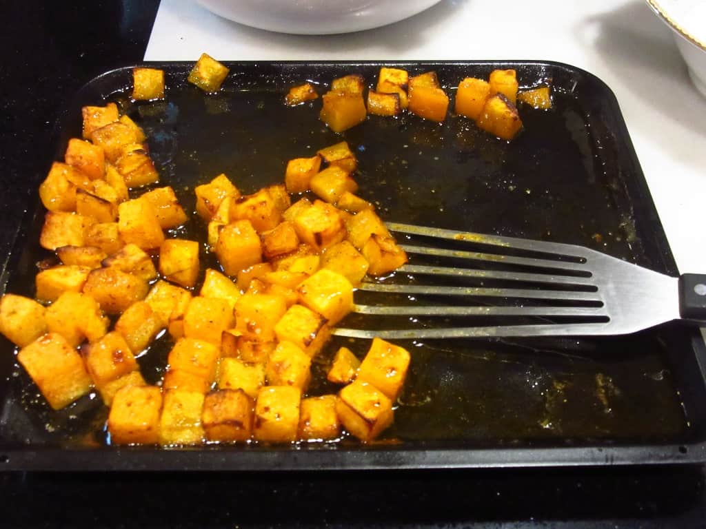 Roasted butternut squash on a baking sheet with a spatula.