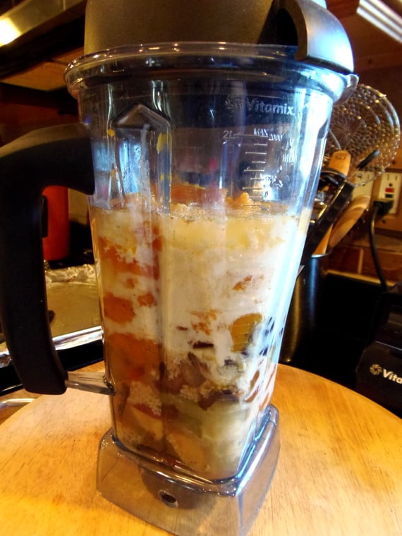 A vitamix blender with soup ingredients inside.