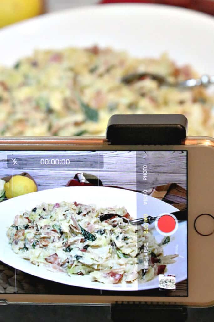 A vertical photo of a closeup of an iphone taking a video of Creamed Cabbage and Spinach recipe