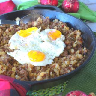 A vertical photo of Grinch Who Hash in a cast iron skillet with green napkins and red Christmas ornaments