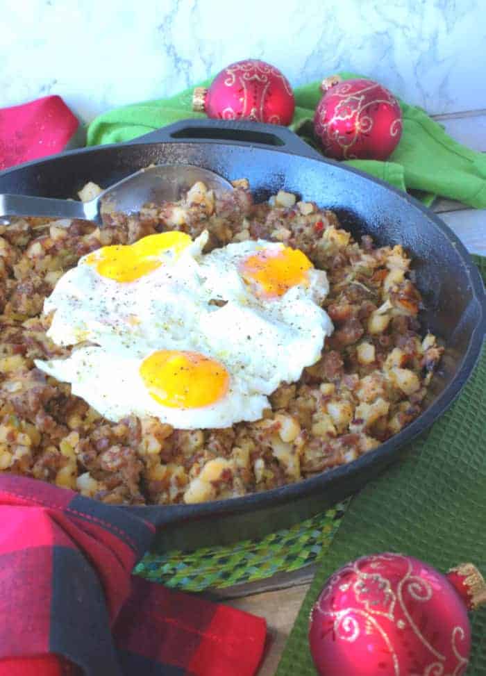 A vertical photo of a cast iron skillet filled with Grinch Who Hash with fried eggs on top.