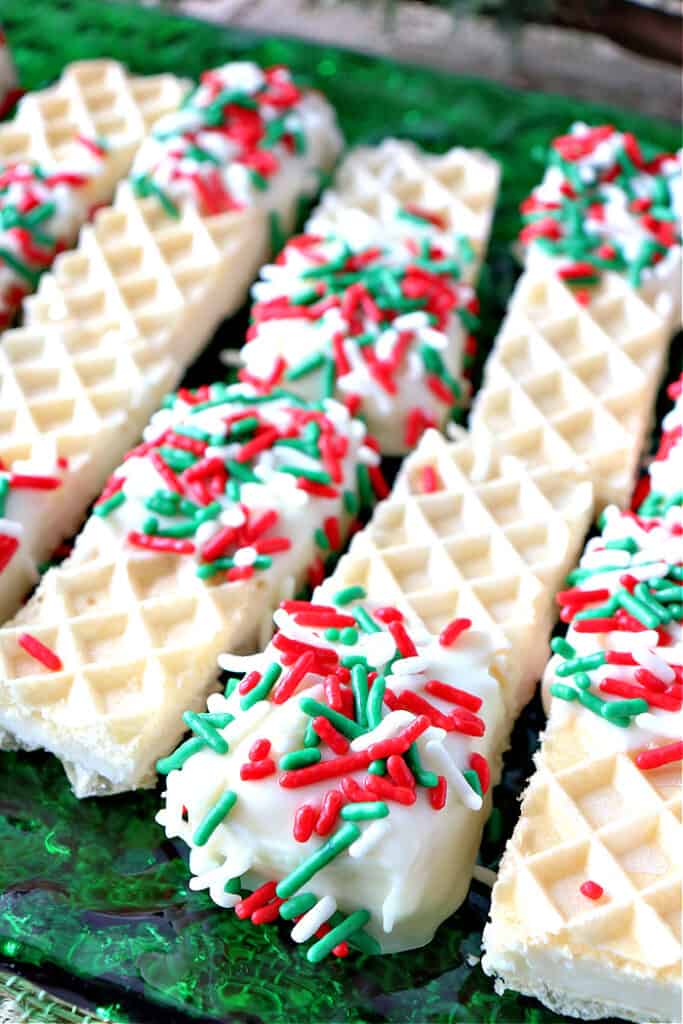Closeup vertical image of No-Bake Peppermint Buttercream Wafer Cookies dipped in white chocolate with red and green sprinkles.