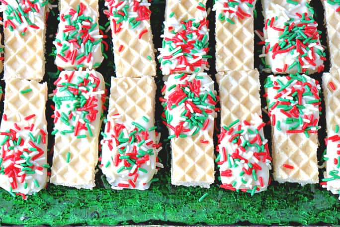 An overhead photo of a green glass plate filled with Peppermint Buttercream Wafer Cookies with red and green sprinkles.