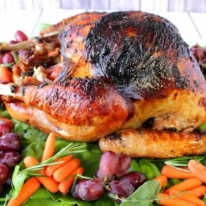 A colorful Make-Ahead Roast Turkey with carrots and grapes surrounding the bird.