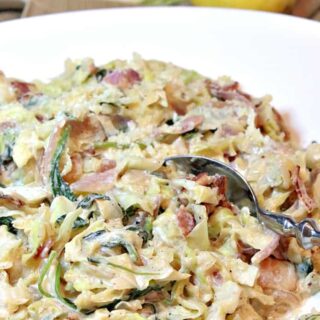 A closeup photo of Creamed Cabbage and Spinach in a white bowl with a serving spoon