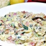 Creamed Cabbage with Spinach and Bacon in a white bowl with a lemon in the background.