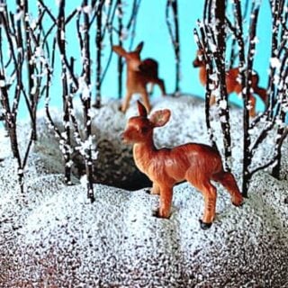 A closeup of a gingerbread forest cake with faux trees and deer