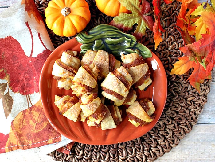 A direct overhead photo of a pumpkin plate filled with Pumpkin Pie Bites along with some autumn leaves for interest.