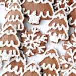 A vertical closeup image of Gingerbread Trees and Snowflake Cookies along with Royal Icing Decorations