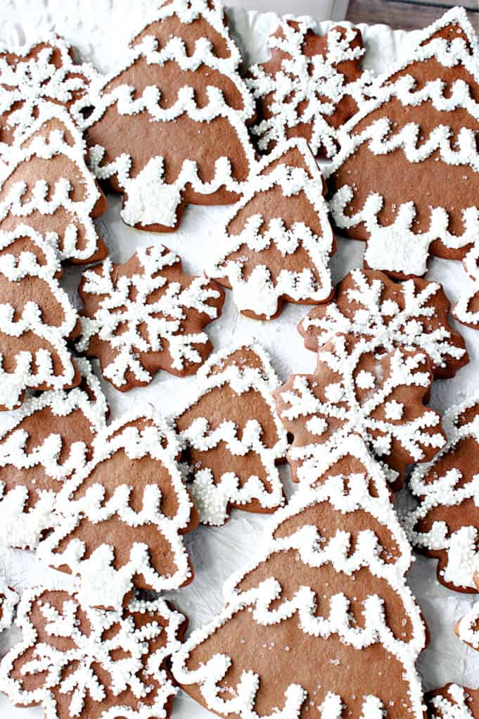 A vertical closeup picture of brown and white Gingerbread Cookies with royal icing and sanding sugar.