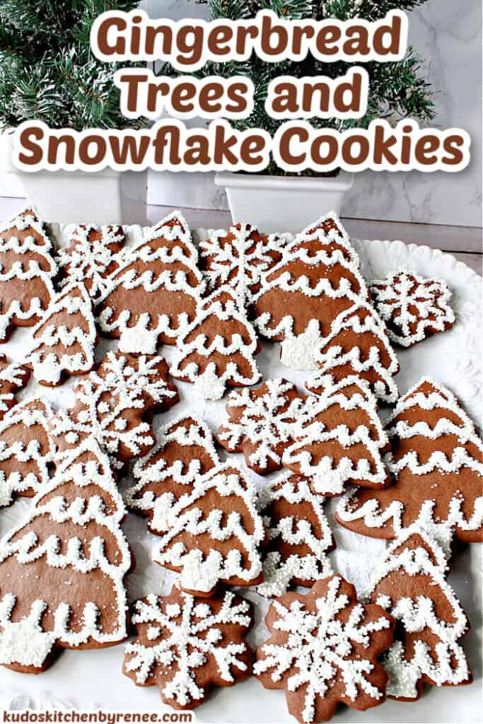 A vertical title text image of Gingerbread Trees and Snowflake Cookies on a white platter with snow covered pine trees in the background.