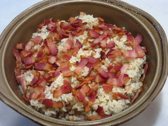 Hoppin' John topped with bacon in a casserole dish.