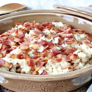 A tan casserole dish filled with Hoppin' John with a spoon and a casserole lid in the background.