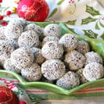 A cute holly berry bowl filled with Nonpareil Chocolate Peppermint Truffles with holiday napkins and ornaments on the side.