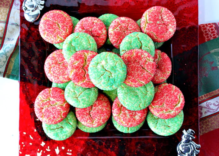 A direct overhead photo of a red glass plate filled with Santa's Favorite Sugar Cookies with red and green sugars.