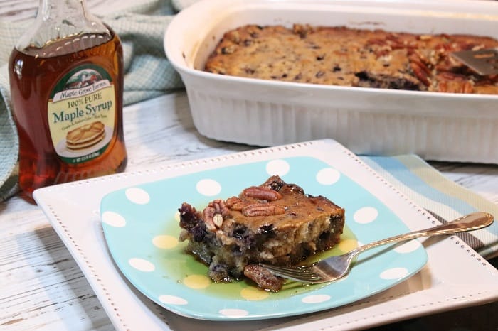 A square of Blueberry Sausage Breakfast Casserole on a blue polka dot plate with maple syrup.