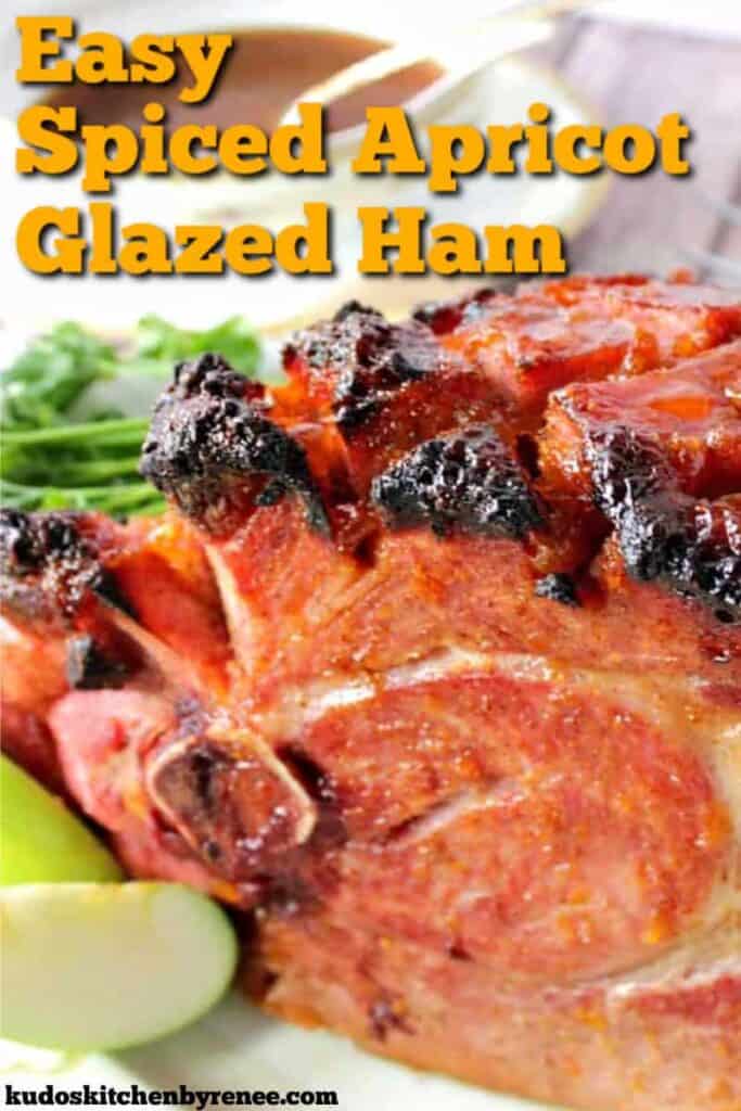 A closeup vertical photo of a Spiced Apricot Glazed Ham with fresh apple slices and a title text overlay graphic.