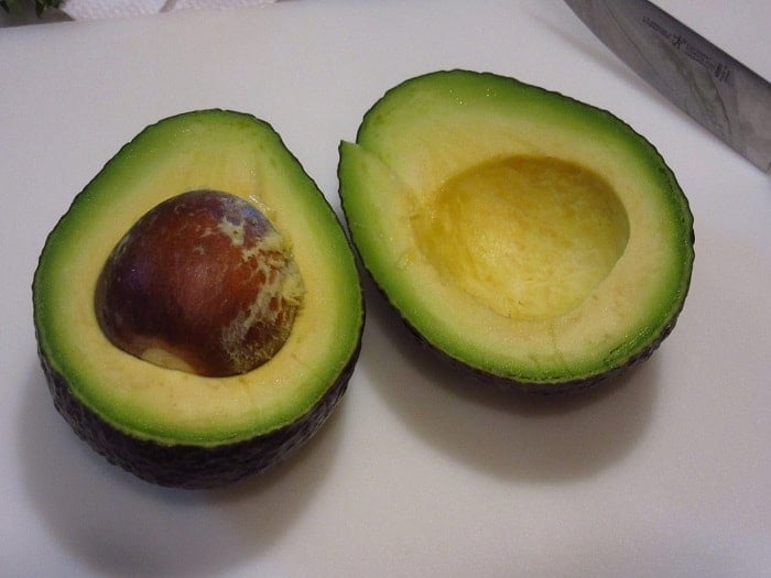 An avocado that's been cut in half and the pit is still inside.