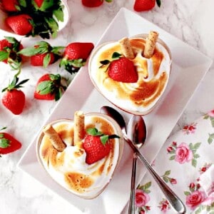 Two heart shaped Baked Alaska for Two with strawberries and spoons.