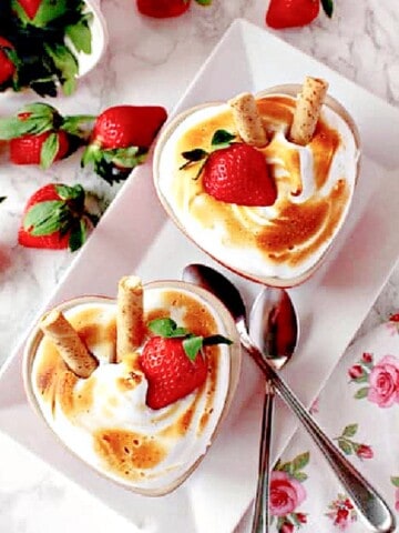 Two heart shaped Baked Alaska for Two with strawberries and spoons.