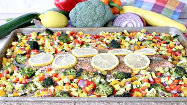 A sheet pan supper of Rainbow Trout with Rainbow Vegetables along with fresh veggies in the background.