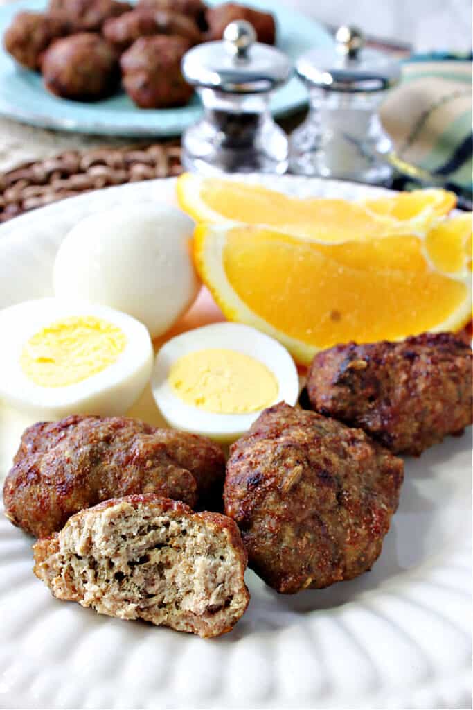 A closeup vertical image of the inside of a Turkey Breakfast Sausage along with a hard cooked egg and an orange slice on an white plate.