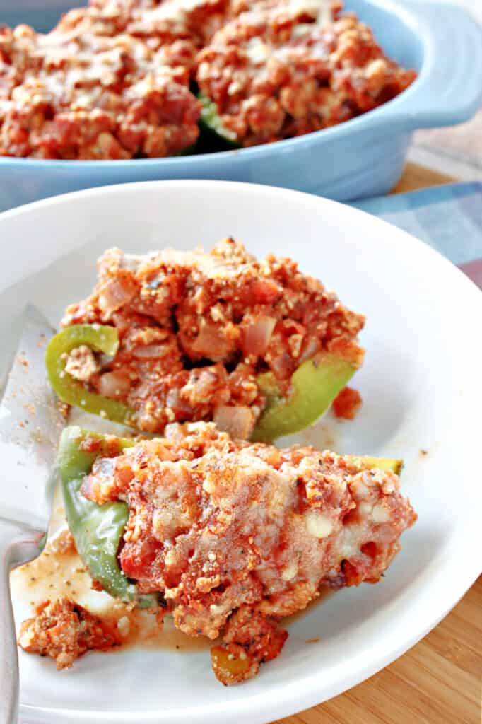 A vertical image of Turkey Parmesan Stuffed Peppers in a white bowl with a blue casserole dish in the background.