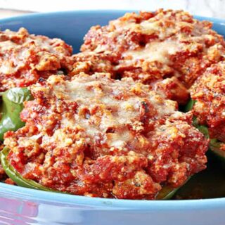 A blue casserole dish filled with baked Turkey Parmesan Stuffed Peppers.