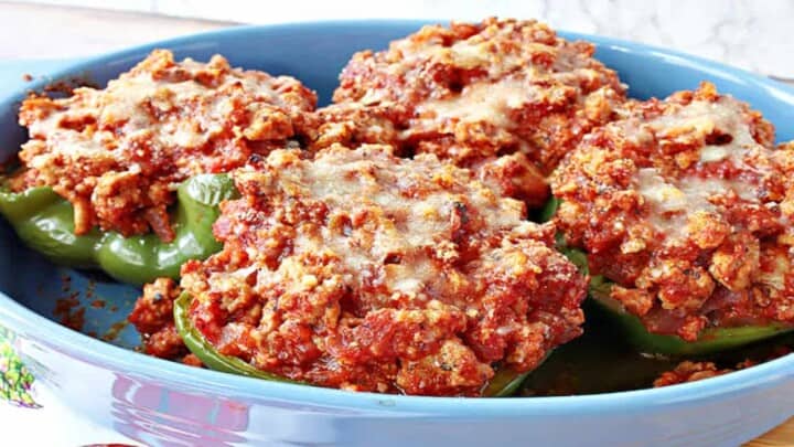 A blue casserole dish filled with baked Turkey Parmesan Stuffed Peppers.