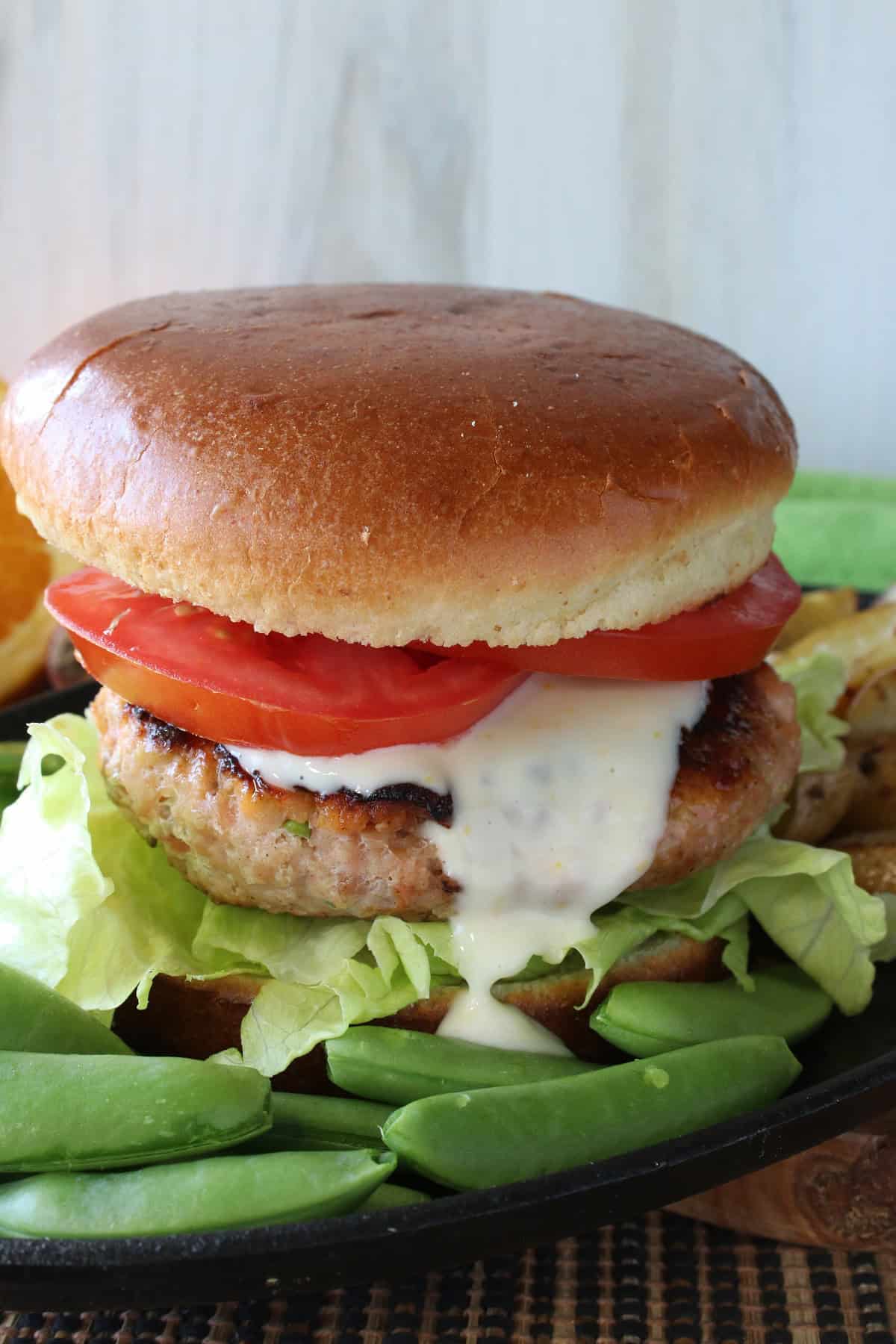 A Salmon Burger with Miso and Sugar Snap Peas on a plate with lettuce.