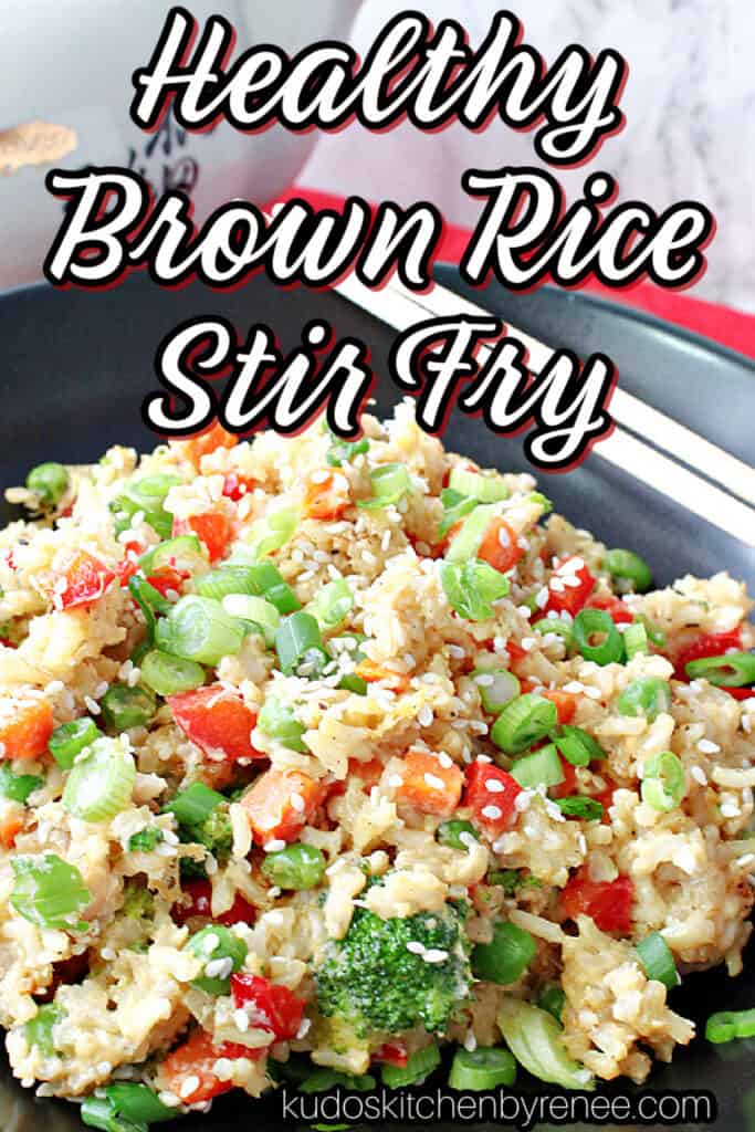A vertical closeup of a healthy dish of Brown Rice Stir Fry with Vegetables and Eggs in a black bowl with a title text overlay graphic.