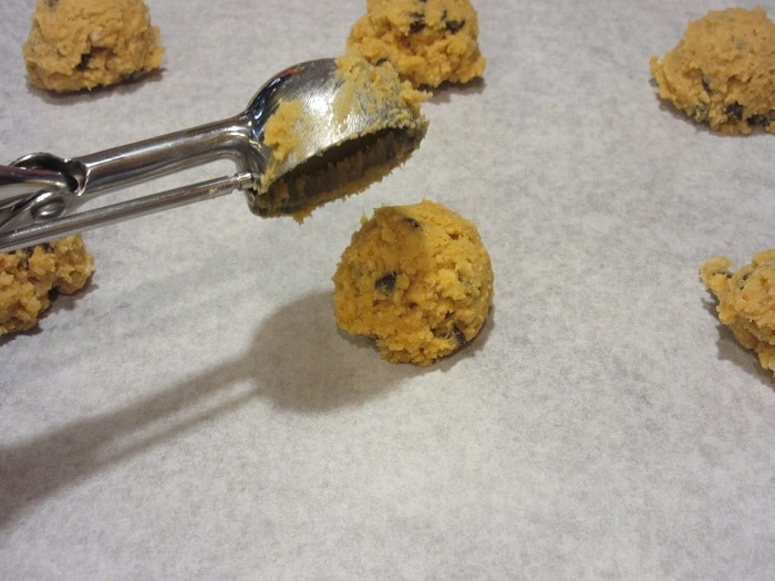 A cookie scoop scooping Butterscotch Ritz Cookies onto parchment paper.