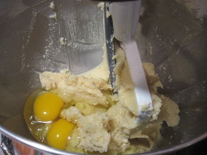 Egg in a bowl with creamed butter and sugar.
