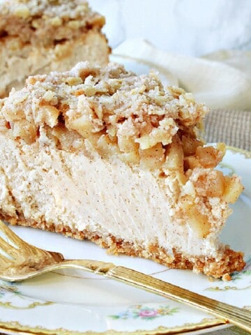 A slice of Dutch Apple Cheesecake on a pretty plate with a fork.