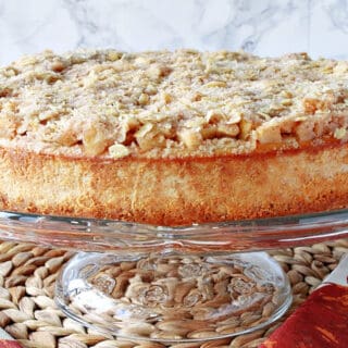 A whole Dutch Apple Cheesecake on a glass cake stand.