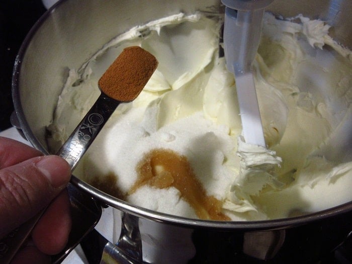 Ground cinnamon being added to a stand mixer.