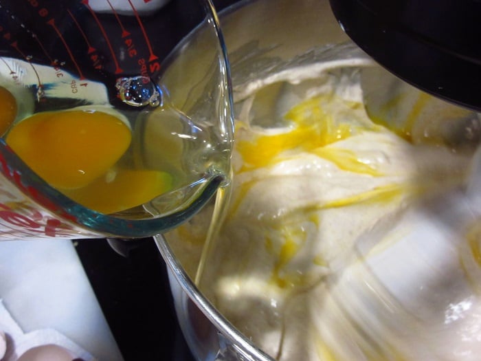 Eggs being added to a cheesecake filling.