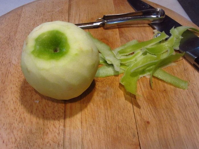 A granny smith apple on a cutting board.