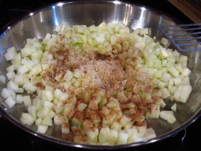 Diced apples in a skillet with spices.