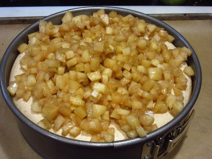 Cooked diced apples on top of a cheesecake.