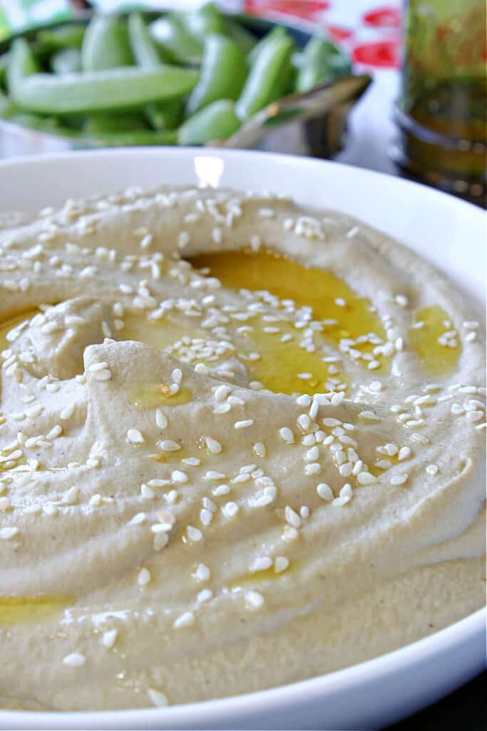 Super closeup vertical photo of Eggplant and Chickpea Hummus along with a drizzle of olive oil and a sprinkling of sesame seeds.