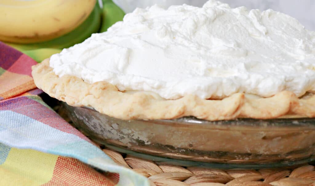 A side view of a Banana Cream Pie with whipped cream.